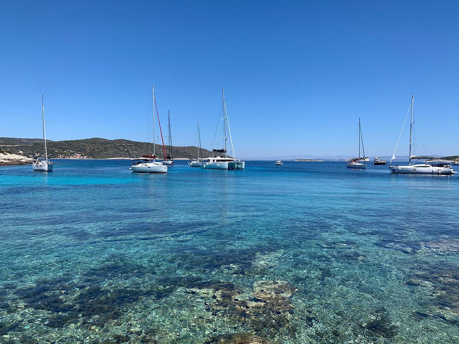 a group of sailboats are floating on top of a clear blue ocean