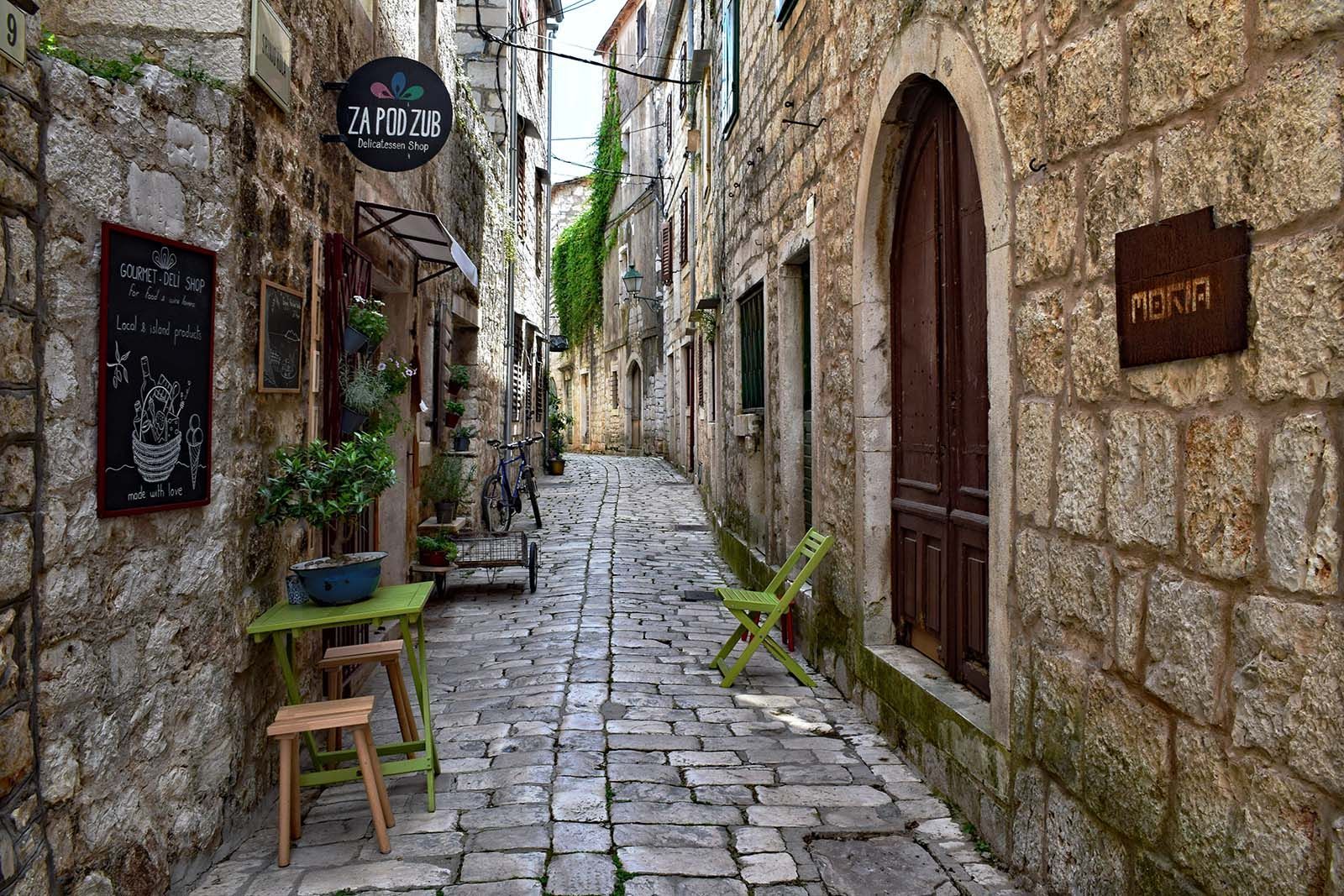 a stone alleyway with a table and chairs in the middle of it