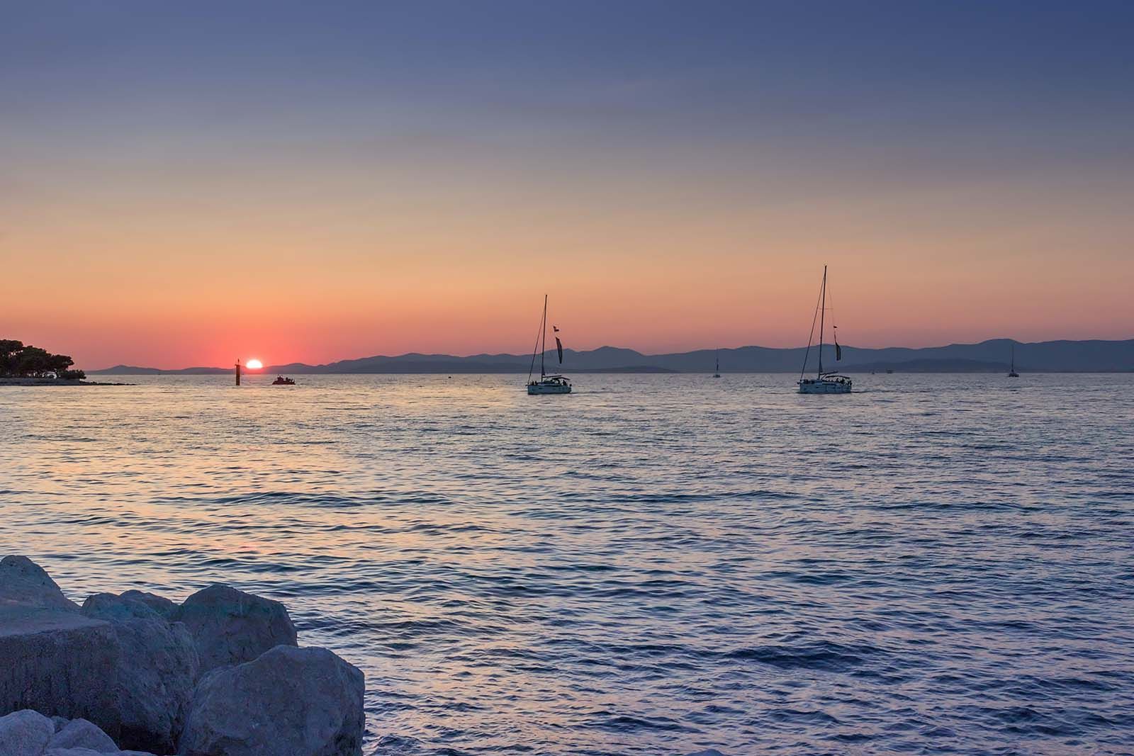 a sunset over a body of water with boats in it