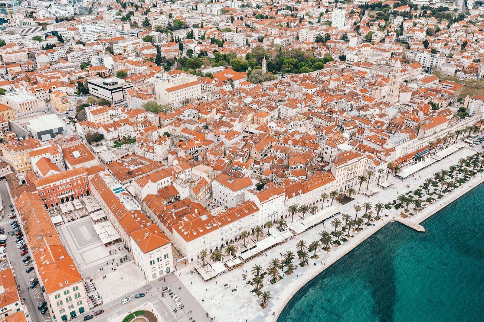 an aerial view of a city with red roofs next to a body of water