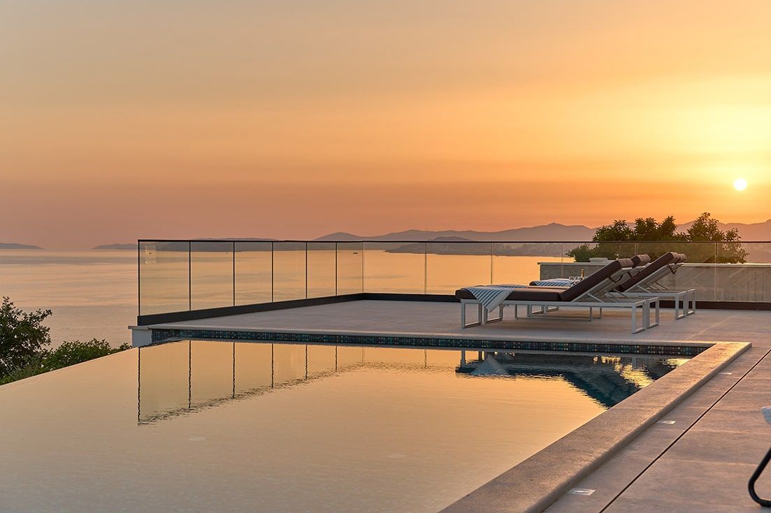 there is a swimming pool with a view of the ocean at sunset