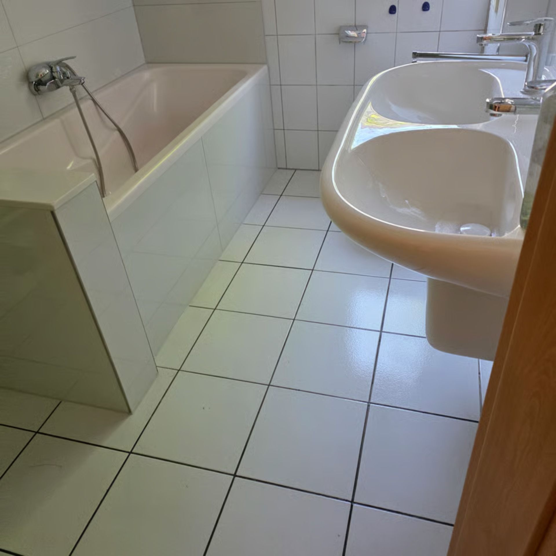 Badezimmer mit weißen Fliesen, Badewanne und Doppelwaschbecken.