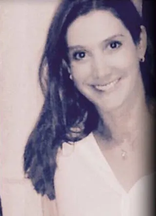Una mujer con una camisa blanca sonríe en una foto en blanco y negro.