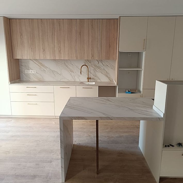 Una cocina con gabinetes de madera y encimera de mármol.
