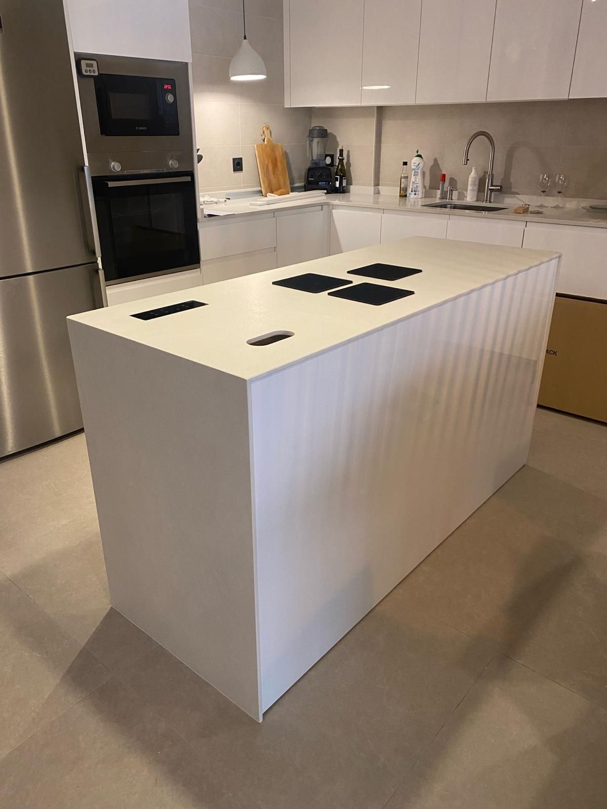 Una cocina con encimera negra y gabinetes blancos.