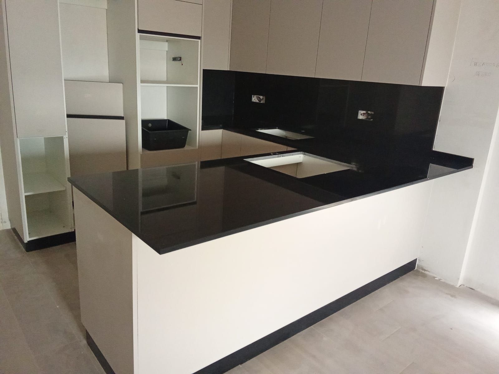 Una cocina con encimeras negras y gabinetes blancos.