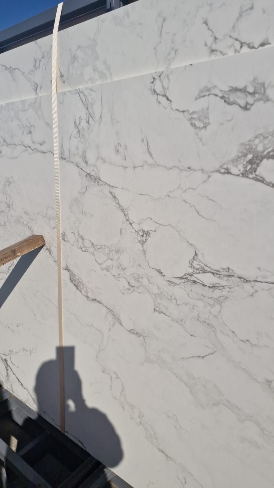 Se está instalando una gran losa de mármol blanco en una pared.