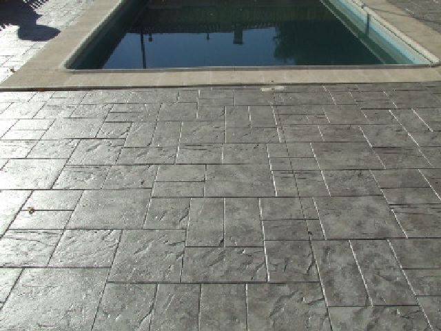 Una piscina está rodeada por una pasarela de ladrillos.
