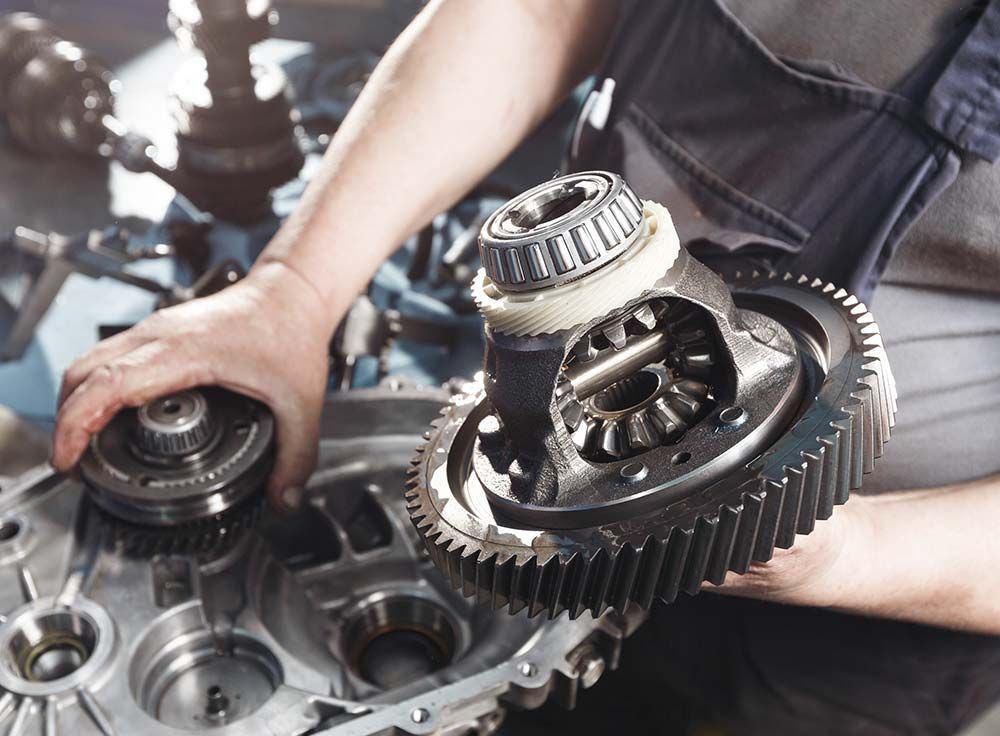 Un hombre está trabajando en una caja de cambios en un garaje.