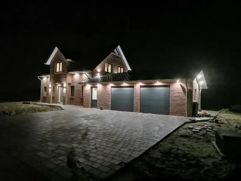 Ein großes Backsteinhaus mit zwei Garagen ist nachts beleuchtet.