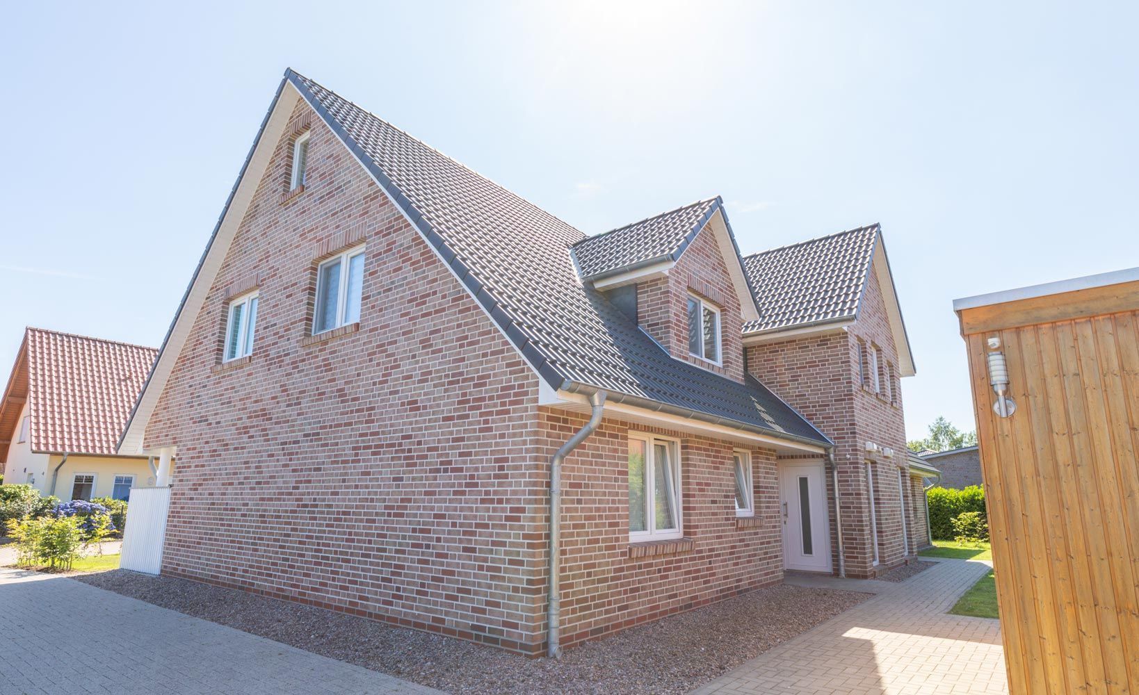 Ein Backsteinhaus mit einer Holzgarage davor.