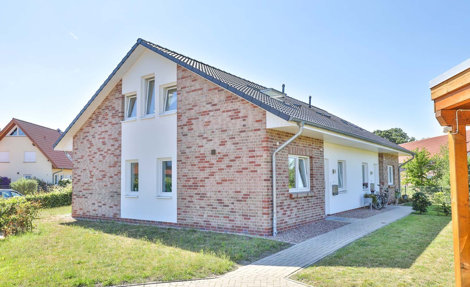 Ein Backsteinhaus mit weißem Dach und einem Gehweg, der dorthin führt.