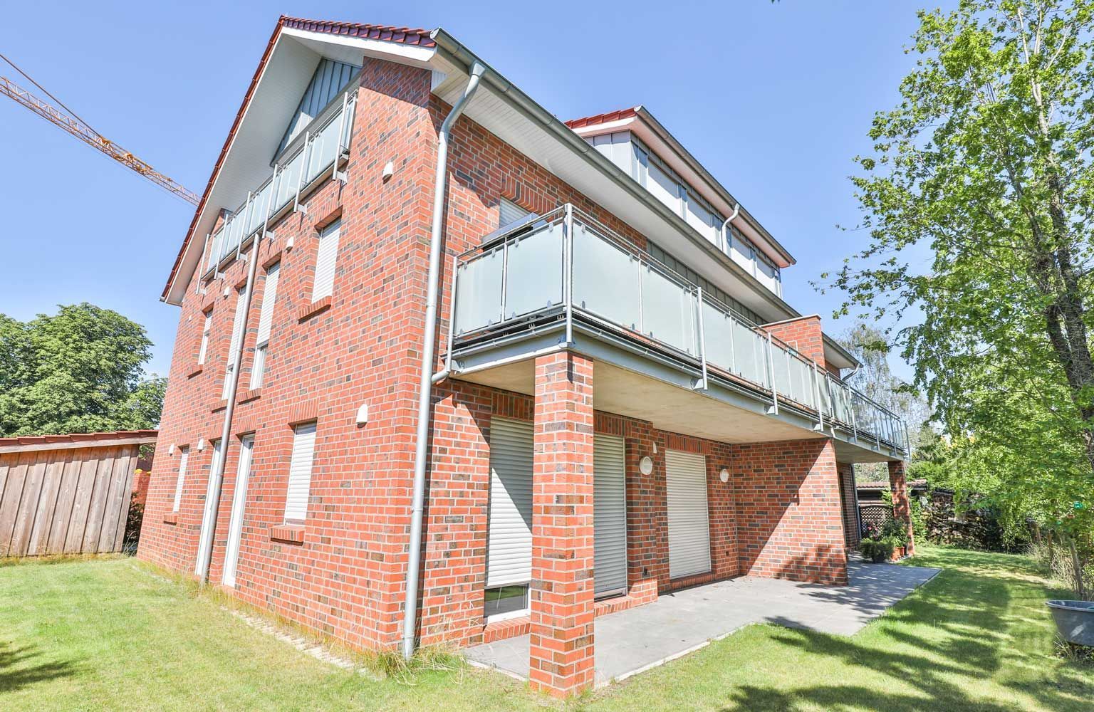 Ein großes rotes Backsteinhaus mit einem Balkon und einem Kran im Hintergrund.