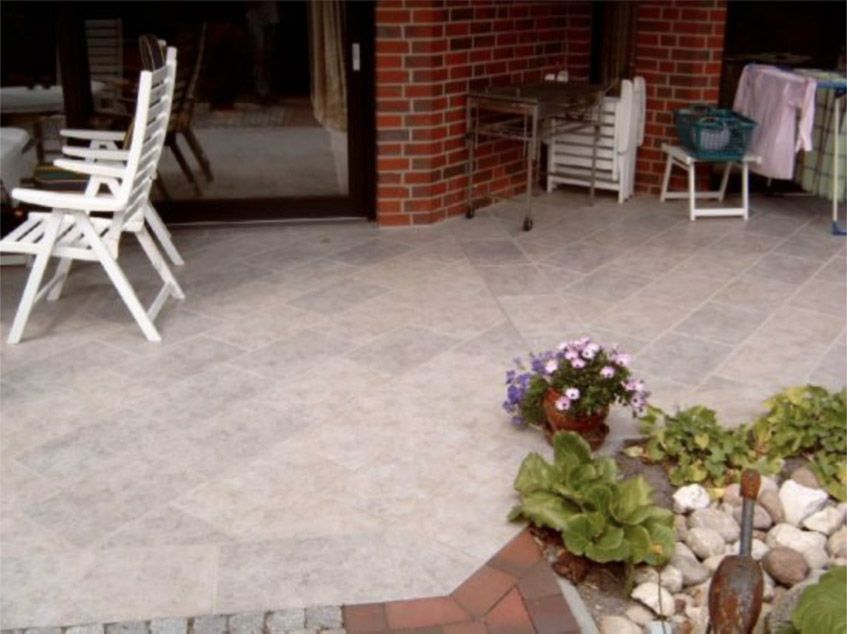 Eine Terrasse mit Stühlen und Blumen vor einer Backsteinmauer