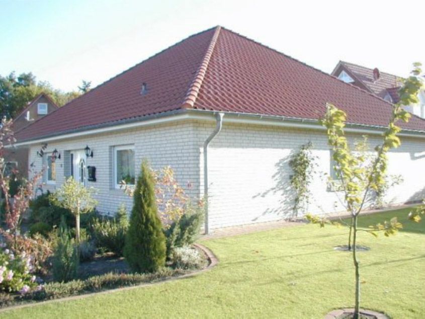 Ein weißes Haus mit rotem Dach und einem Baum davor