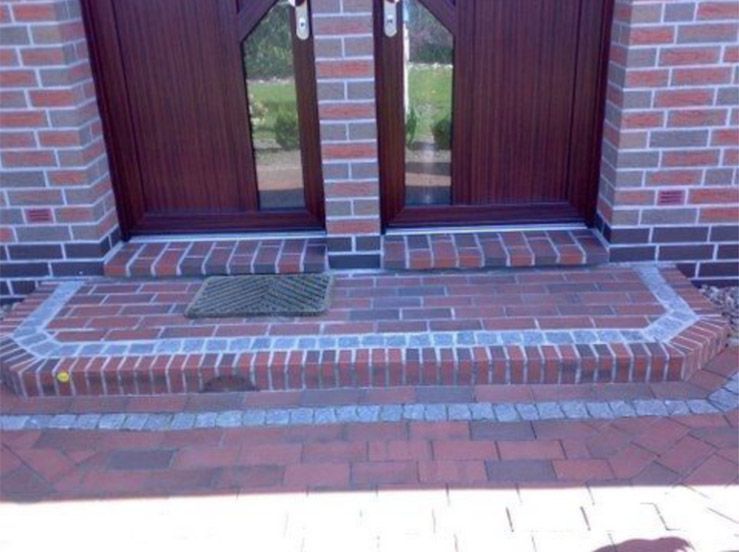 Ein gemauerter Gehweg, der zur Eingangstür eines Hauses führt