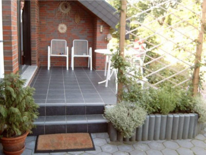 Eine Veranda mit Stühlen und einem Tisch vor einem Backsteingebäude