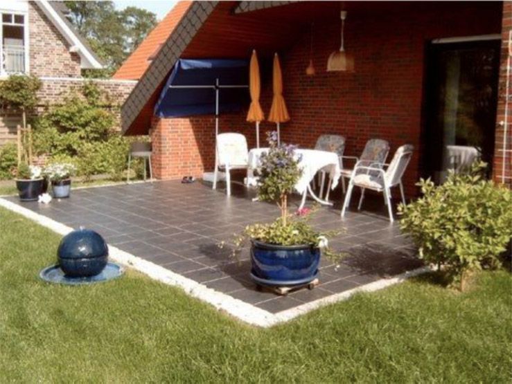 Eine Terrasse mit Stühlen und Sonnenschirmen vor einem Backsteinhaus