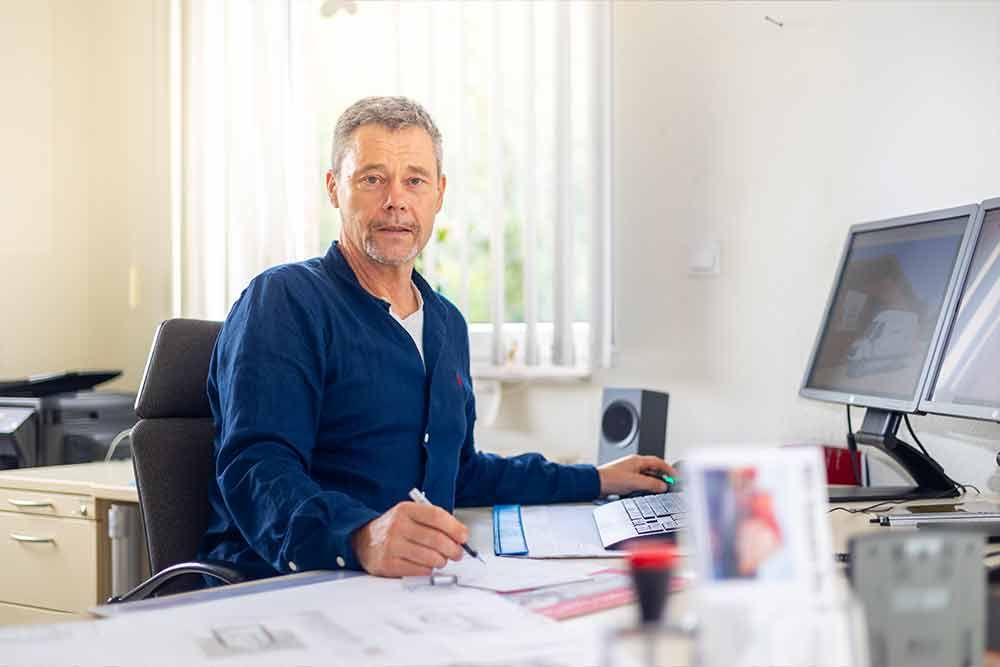 Ein Mann sitzt an einem Schreibtisch vor einem Computer.