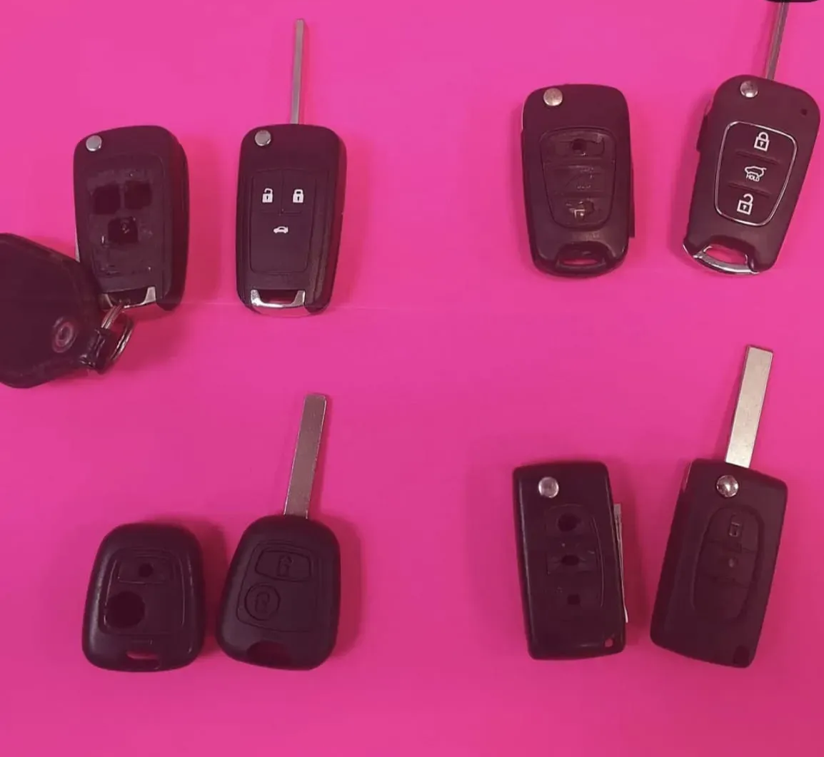 Siete llaves de coche negras sobre una superficie de color rosa brillante.