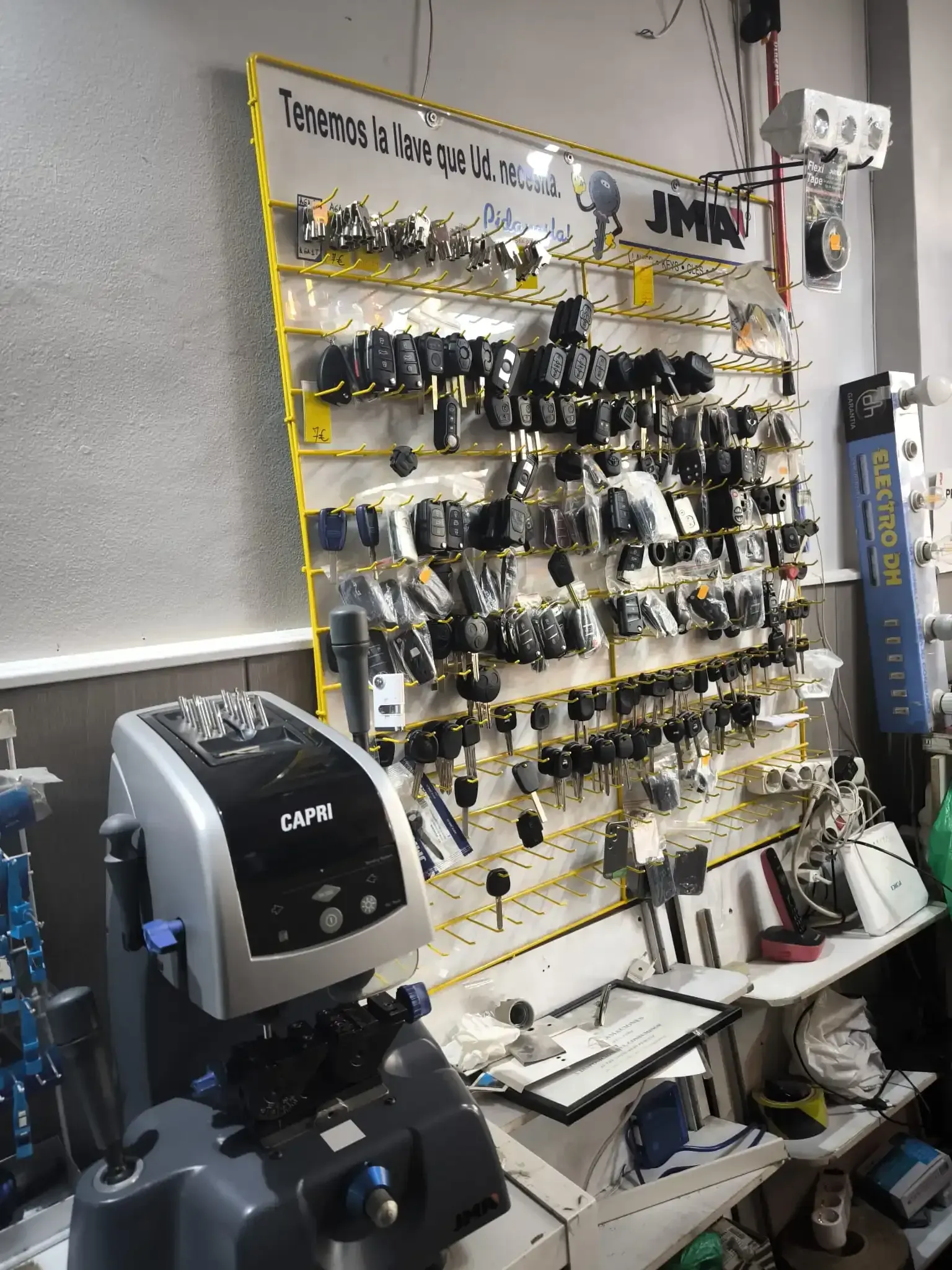 Un taller de fabricación de llaves con un expositor lleno de llaves. En primer plano, una duplicadora.