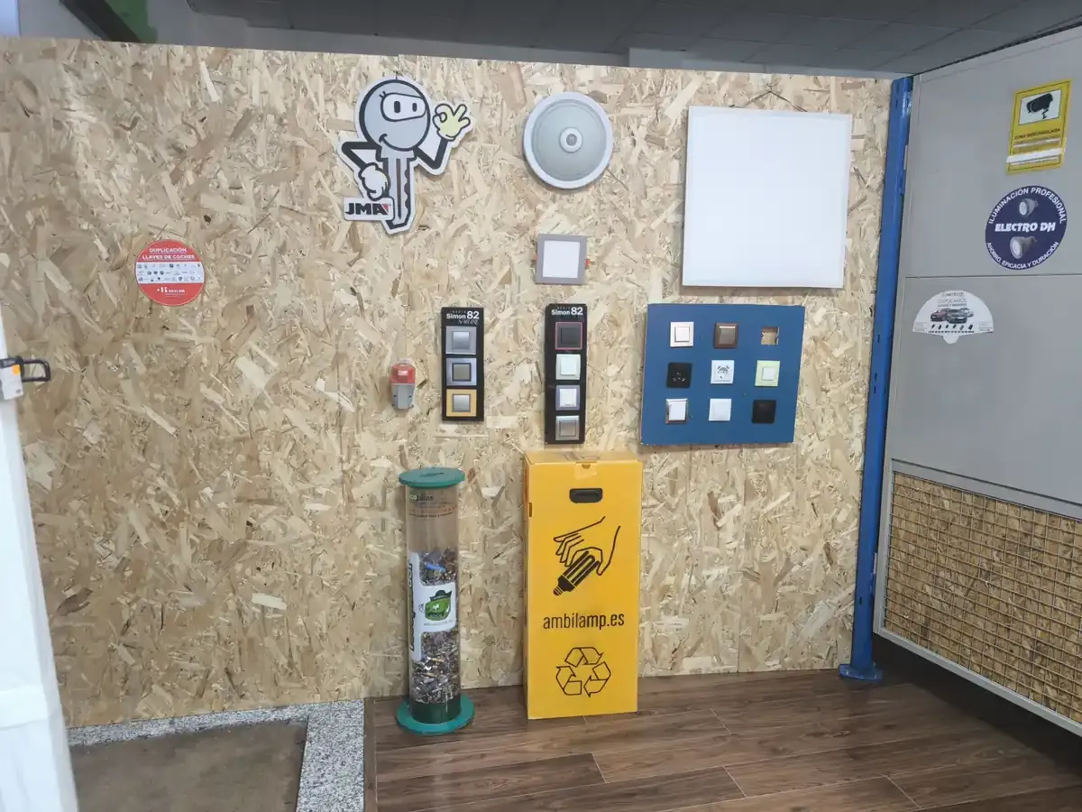 Exposición de pared de componentes eléctricos: interruptores, enchufes y un cubo de basura, sobre un fondo de madera.