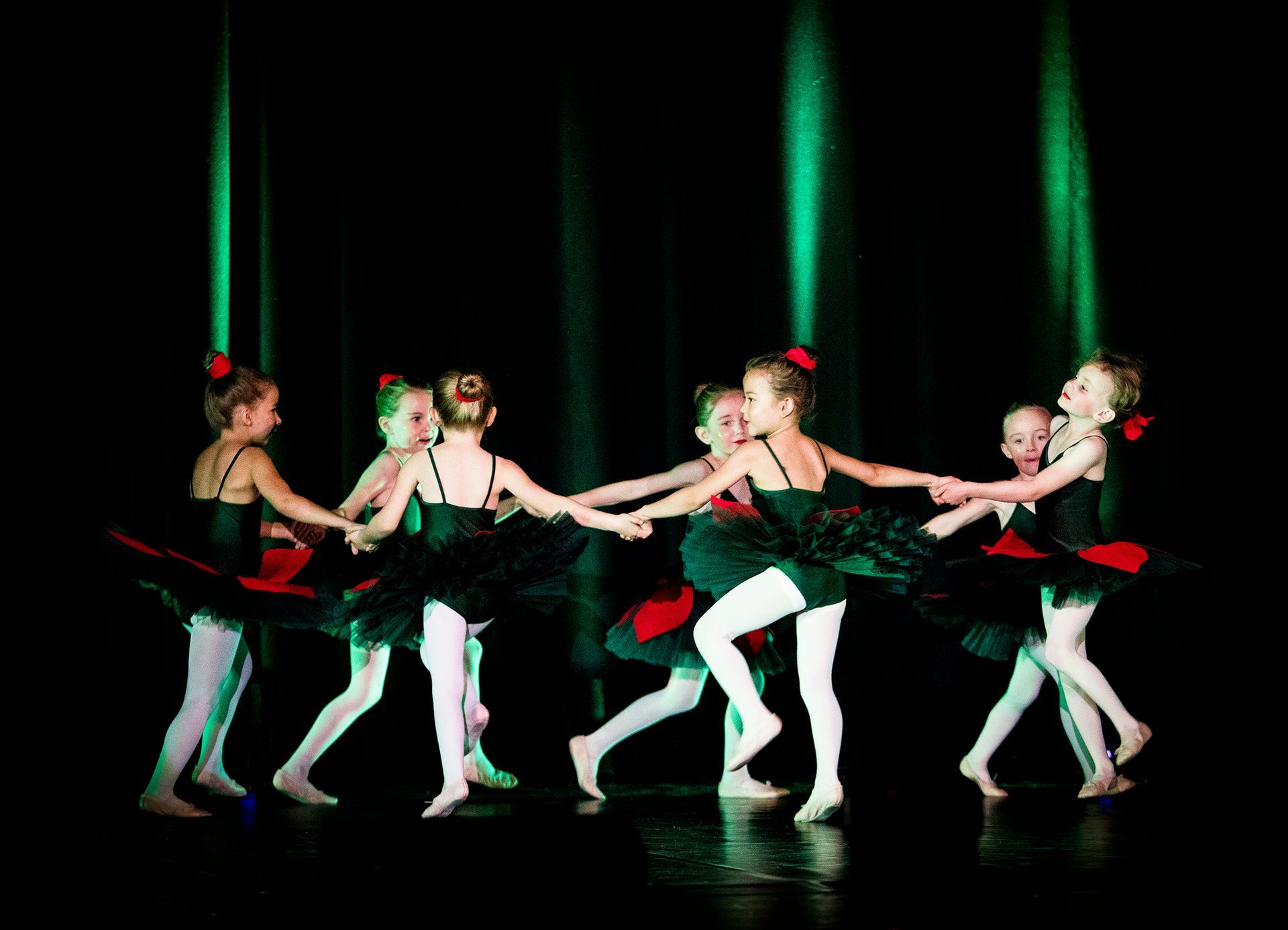 Eine Gruppe junger Ballerinas tanzt im Kreis auf einer Bühne.