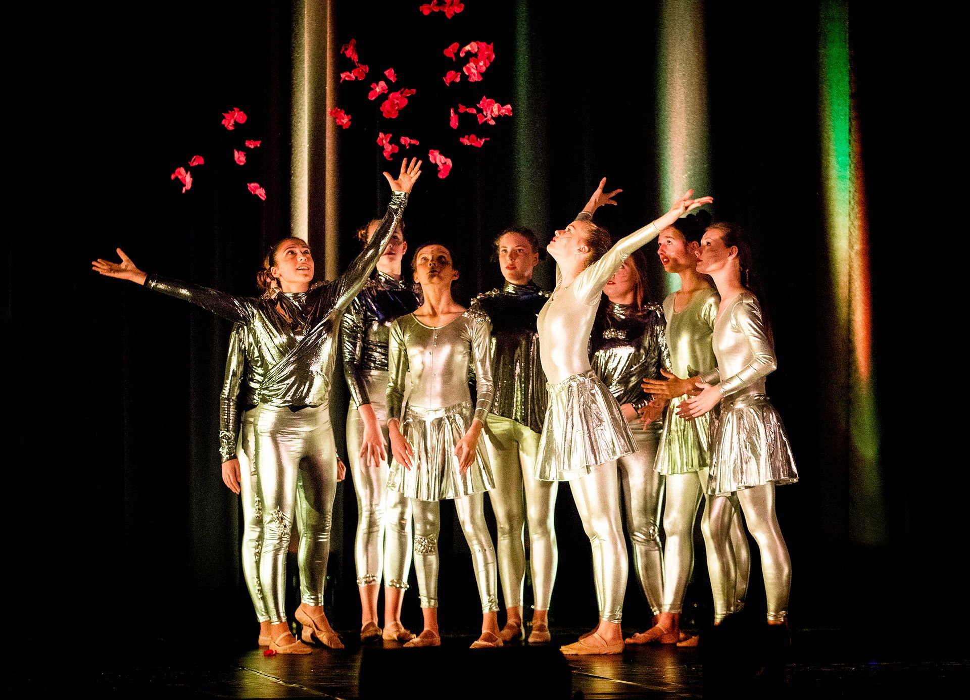 Eine Gruppe von Menschen steht mit erhobenen Armen auf einer Bühne.