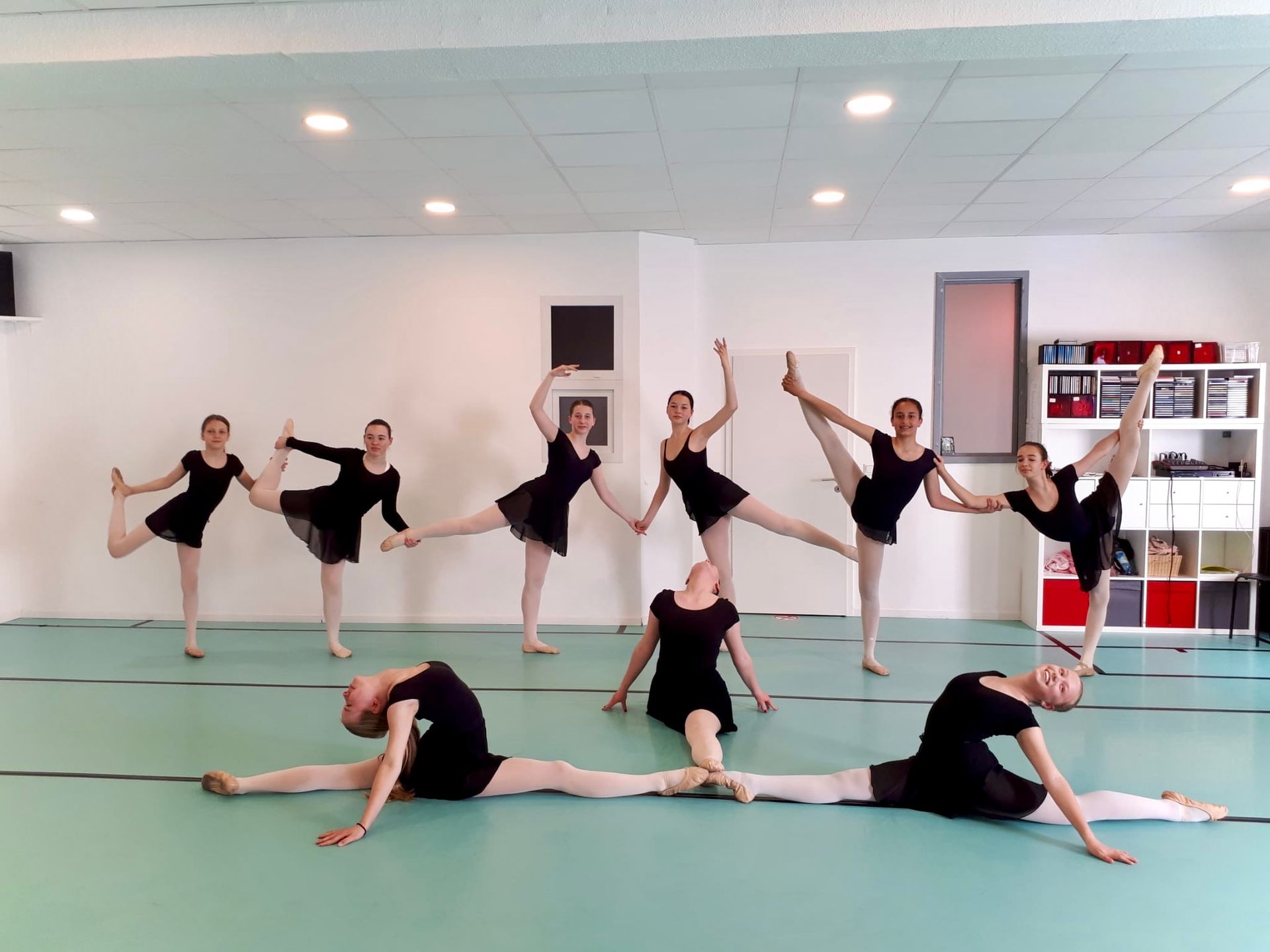 Eine Gruppe junger Frauen macht in einem Tanzstudio Dehnübungen.