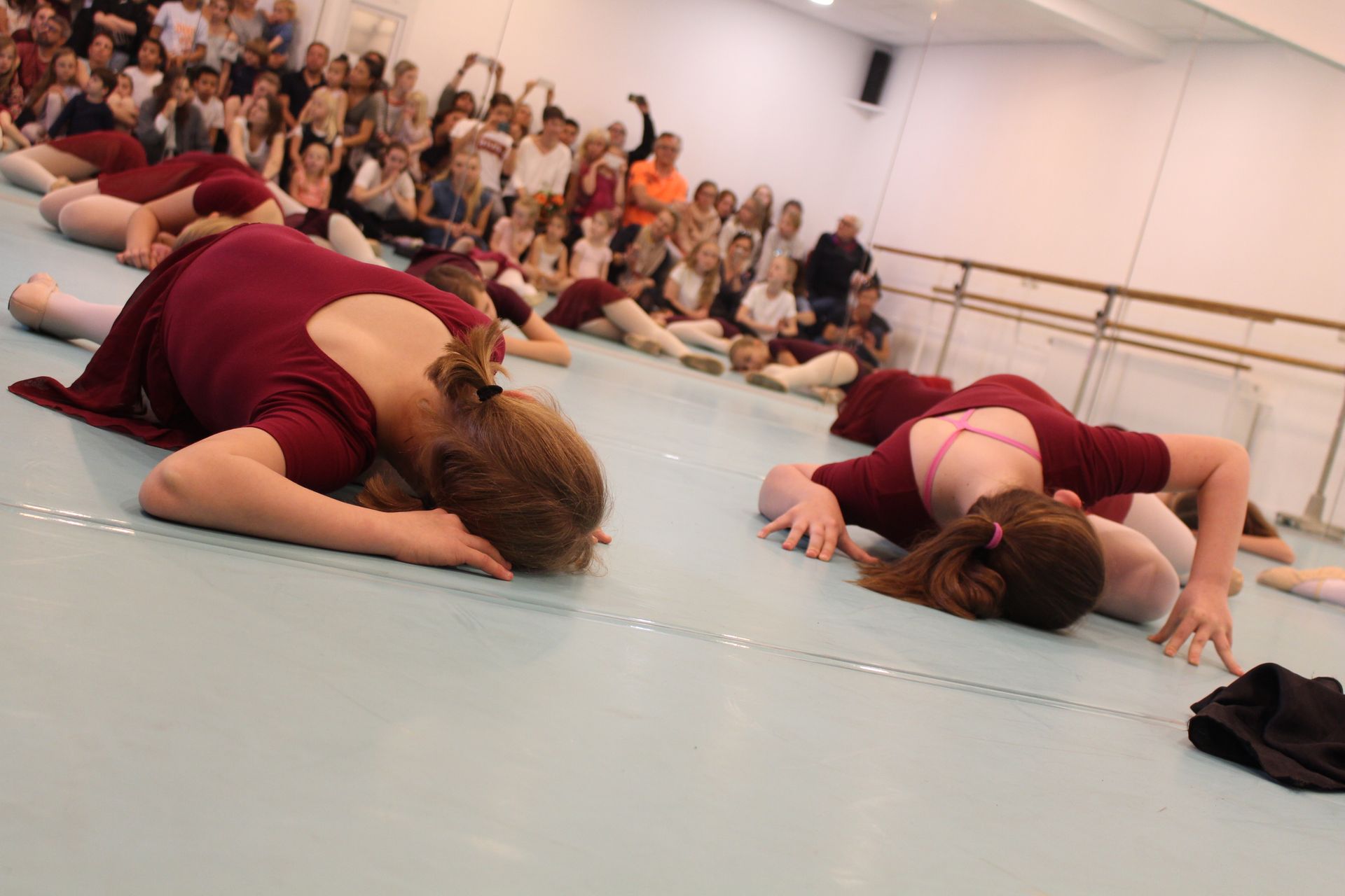 Eine Gruppe junger Mädchen liegt in einem Tanzstudio auf dem Boden.