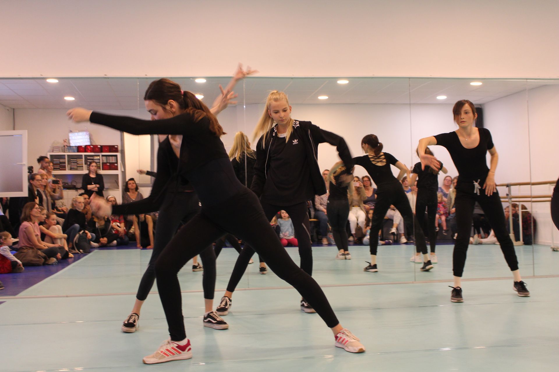 Eine Gruppe junger Frauen tanzt in einem Tanzstudio vor einem Spiegel.