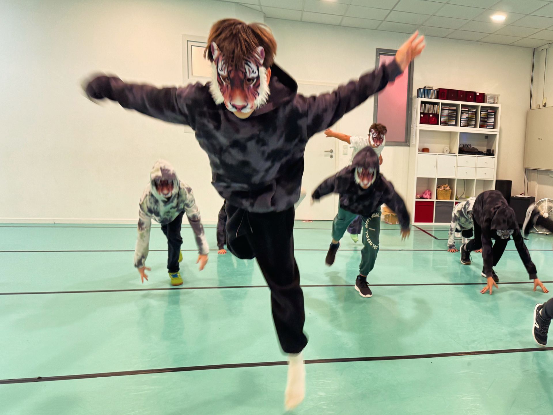 Eine Gruppe Kinder tanzt in einem Tanzstudio und eines von ihnen trägt eine Tigermaske.
