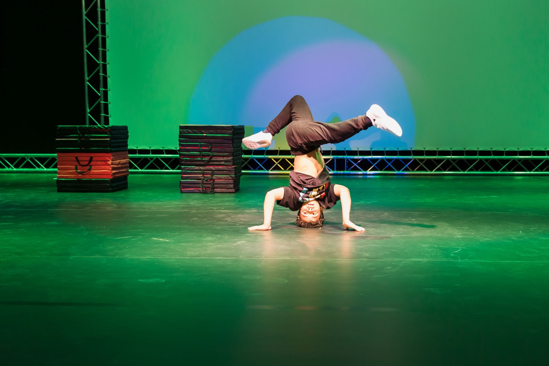 Ein junger Mann macht auf einer Bühne einen Handstand.