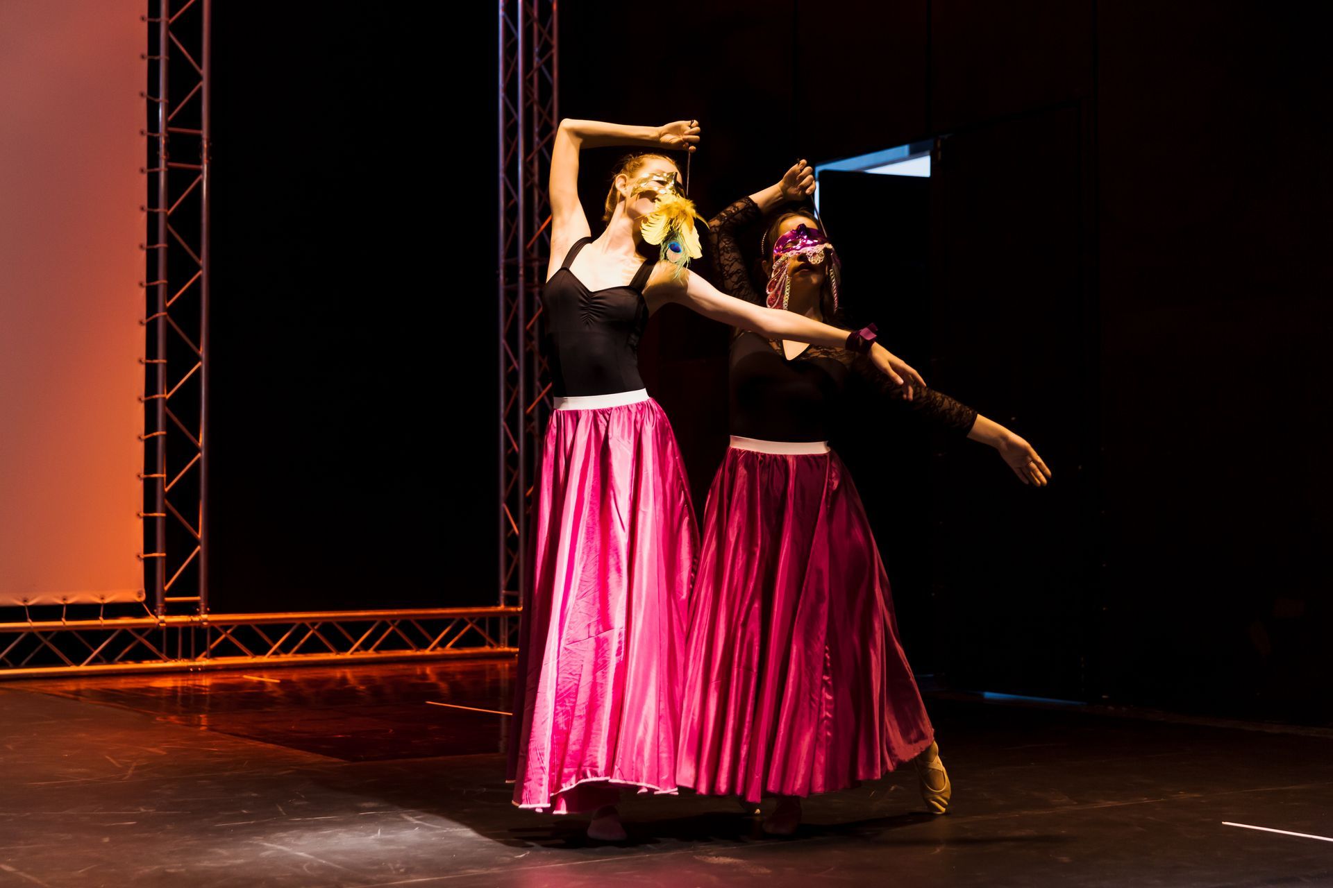 Zwei Frauen in rosa Röcken tanzen auf einer Bühne.