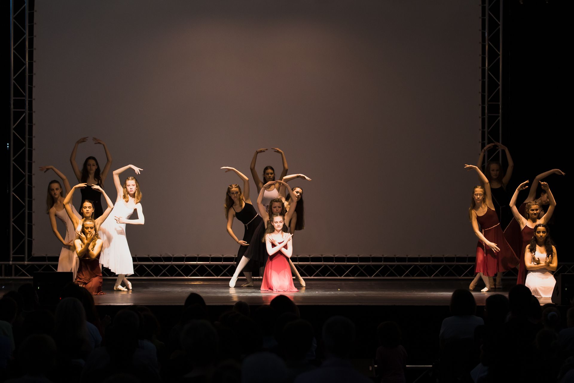 Eine Gruppe Frauen tanzt auf einer Bühne vor einer Menschenmenge.