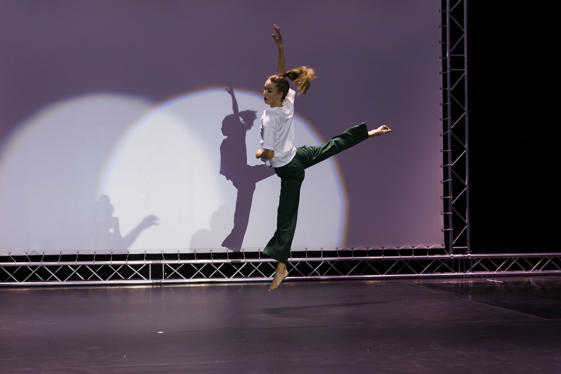 Eine Frau in einem weißen Hemd und einer grünen Hose springt in die Luft.