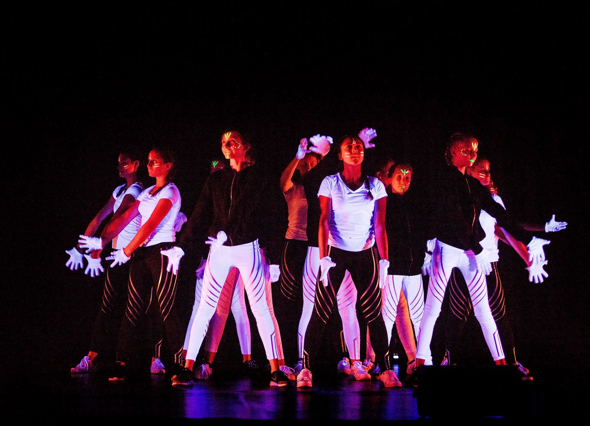 Eine Gruppe von Menschen tanzt in einem dunklen Raum.