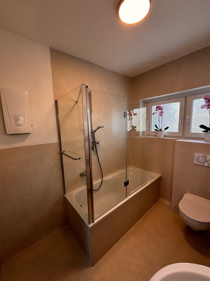 Ein Badezimmer mit Badewanne, Toilette und Fenster.