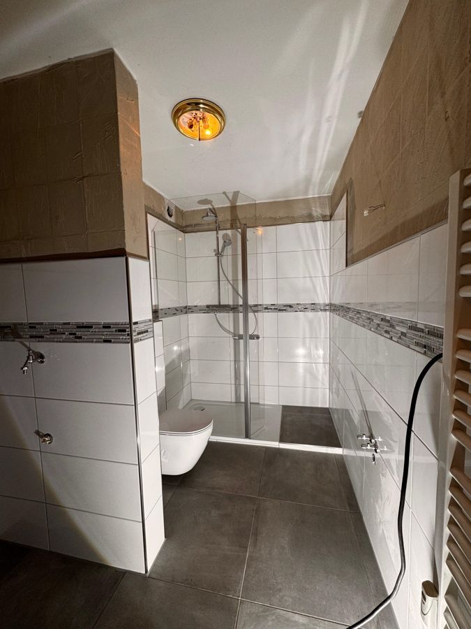 Ein Badezimmer mit Toilette und ebenerdiger Dusche.