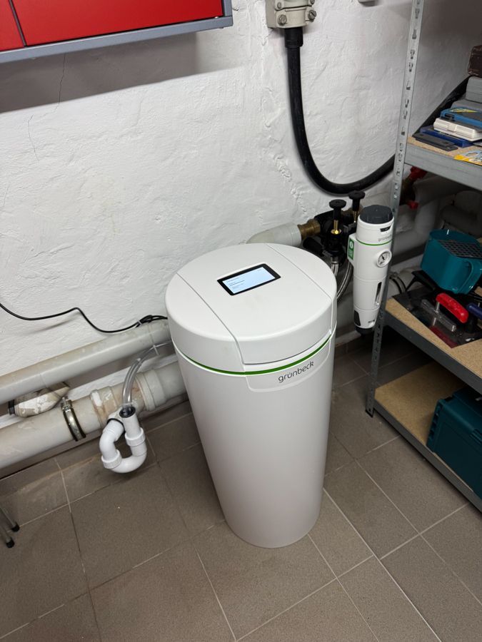 In einem Raum steht auf dem Boden ein weißer Wasserenthärter.