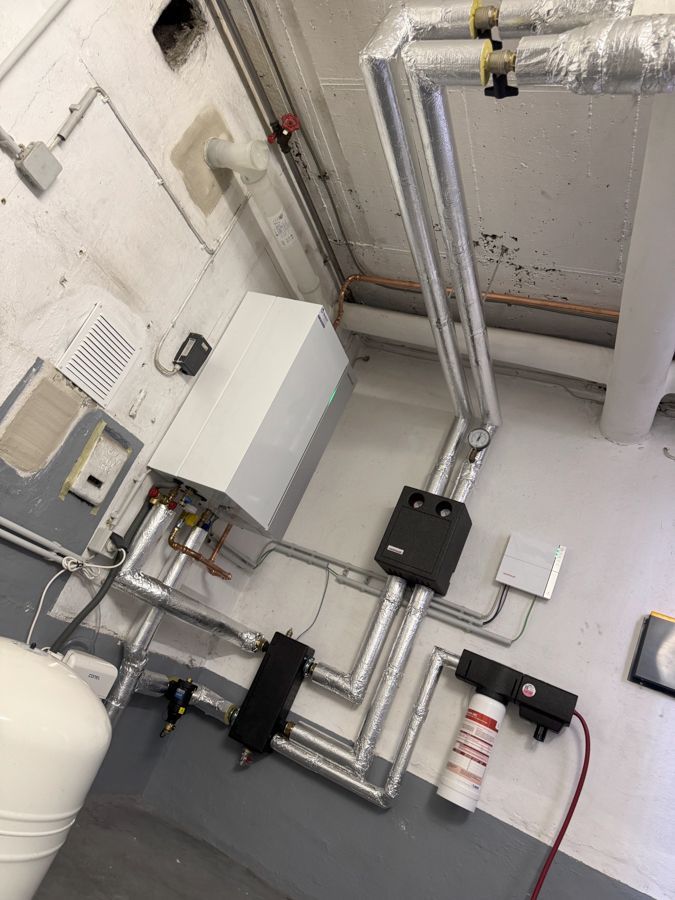 Ein Raum mit vielen Rohren und einem Heizkessel auf dem Boden