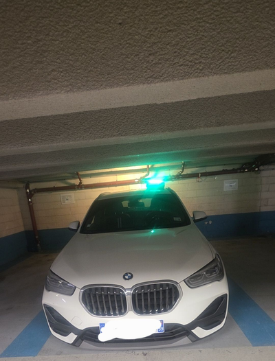 Un SUV BMW garé dans un garage, éclairé par une lumière vive au plafond.