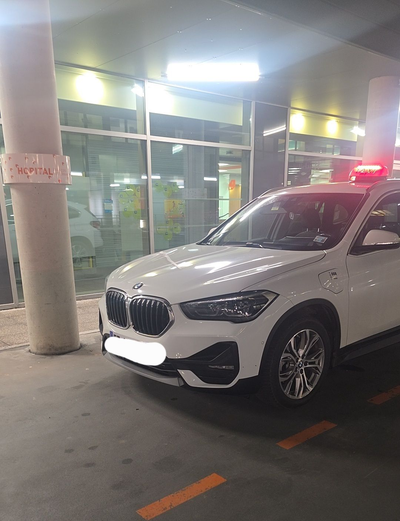Une BMW X1 garée à l'intérieur d'un parking bien éclairé, avec des vitrines en arrière-plan.