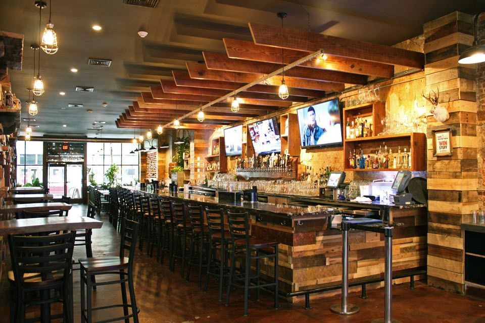 A restaurant with a long bar and tables and chairs.