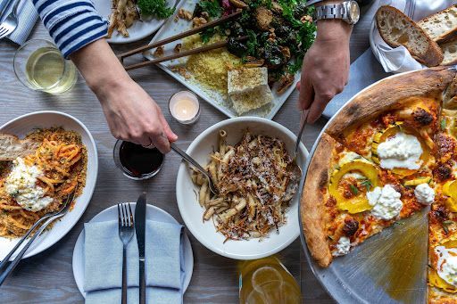 A table topped with plates of food and a pizza.