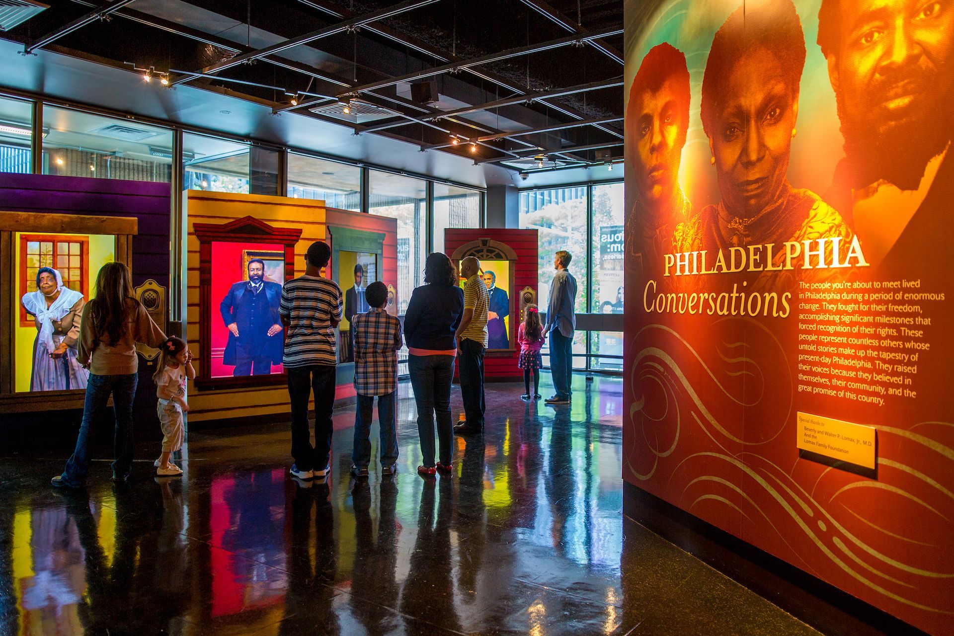A group of people are standing in front of a wall that says philadelphia conversations