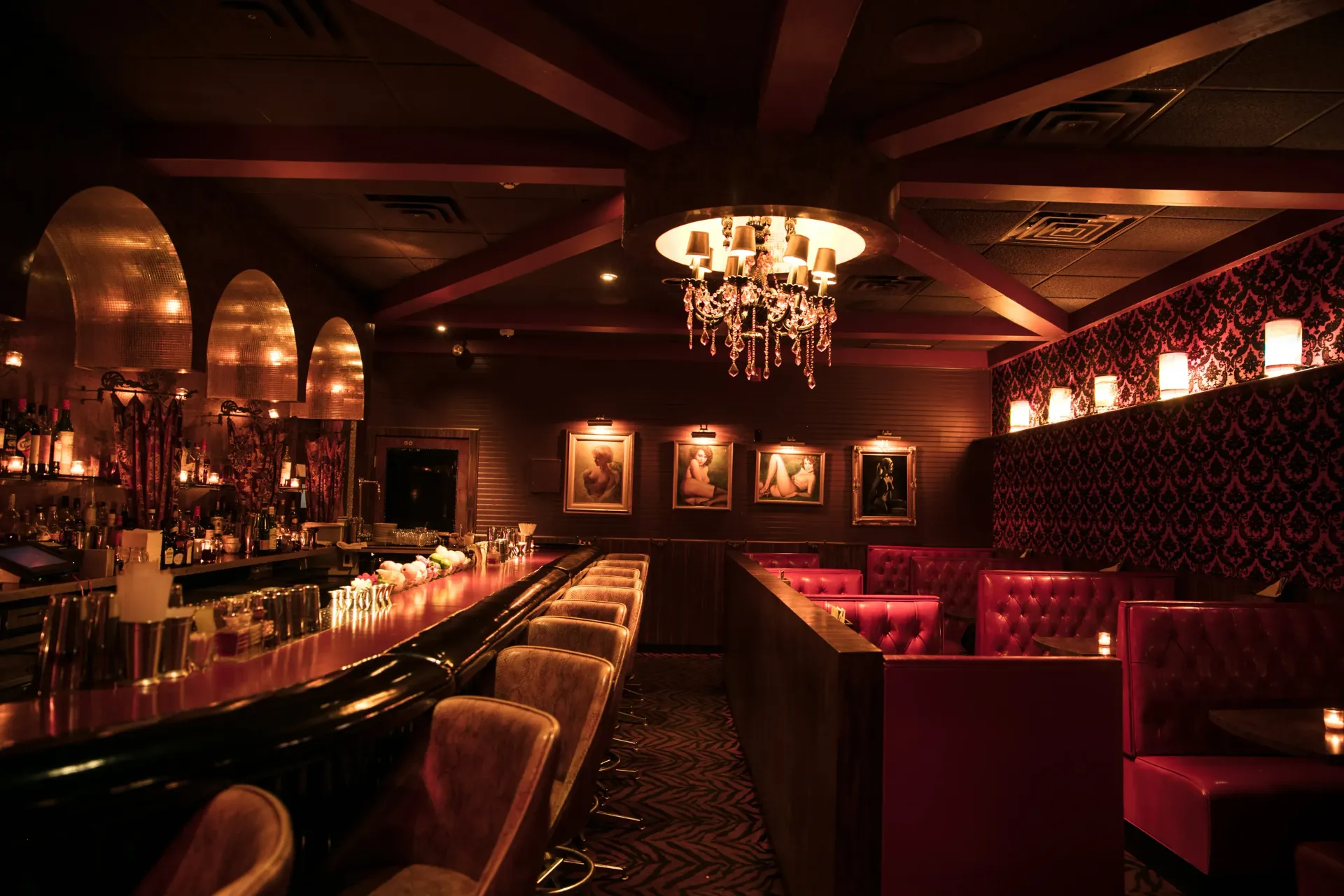 A dark room with a bar and a chandelier