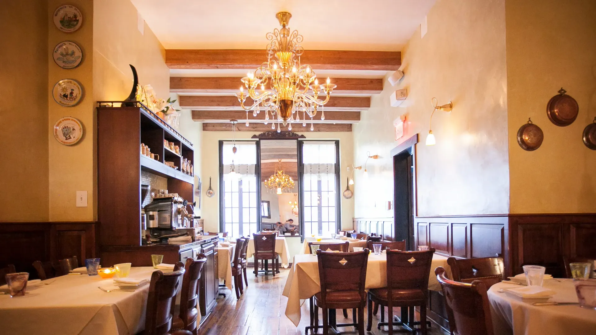 A restaurant with tables and chairs and a chandelier hanging from the ceiling.