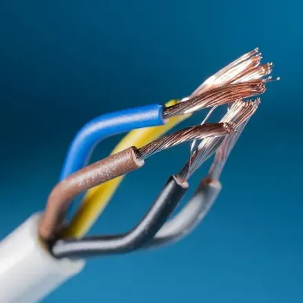 Primer plano de cables eléctricos pelados en color marrón, azul, amarillo y negro, sobre un fondo azul.