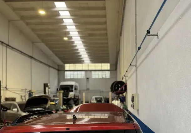 Un coche rojo está aparcado en un garaje con otros coches.
